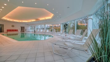 Een binnenzwembad, ligstoelen bij het zwembad