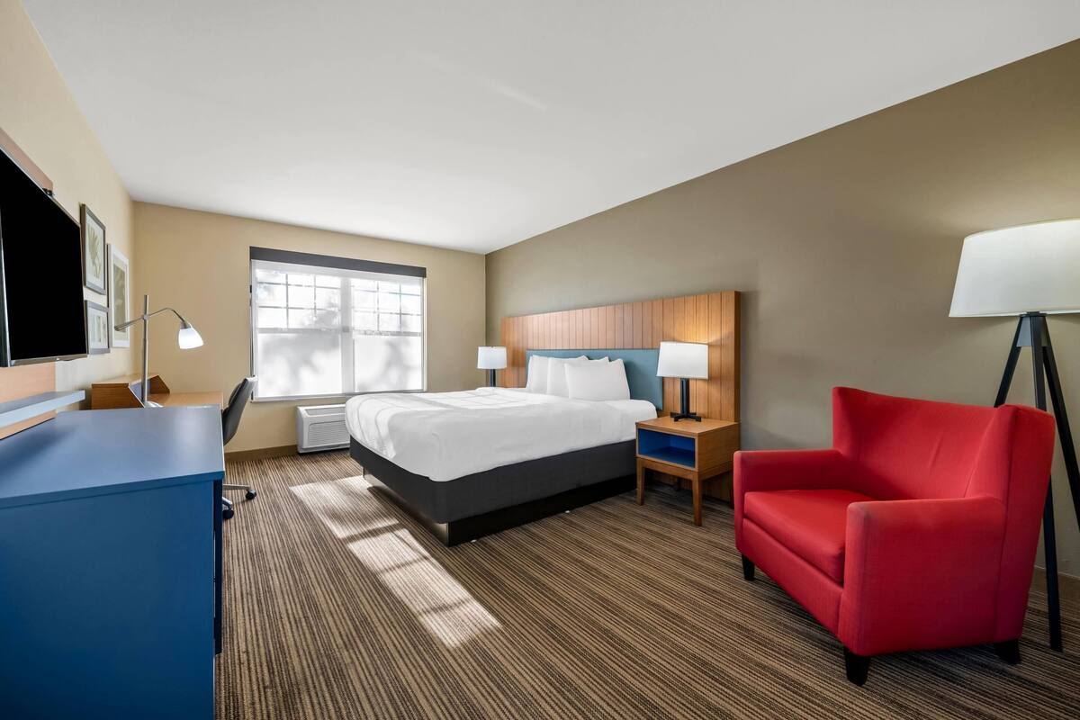Ein Hotelzimmer mit Bett, Schreibtisch, Stuhl und Fenster.