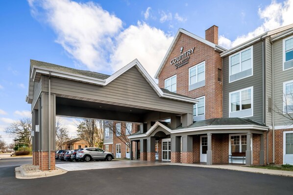 A hotel with a covered entrance, a brick facade, and a sign indicating it is a Radisson Inn & Suites.