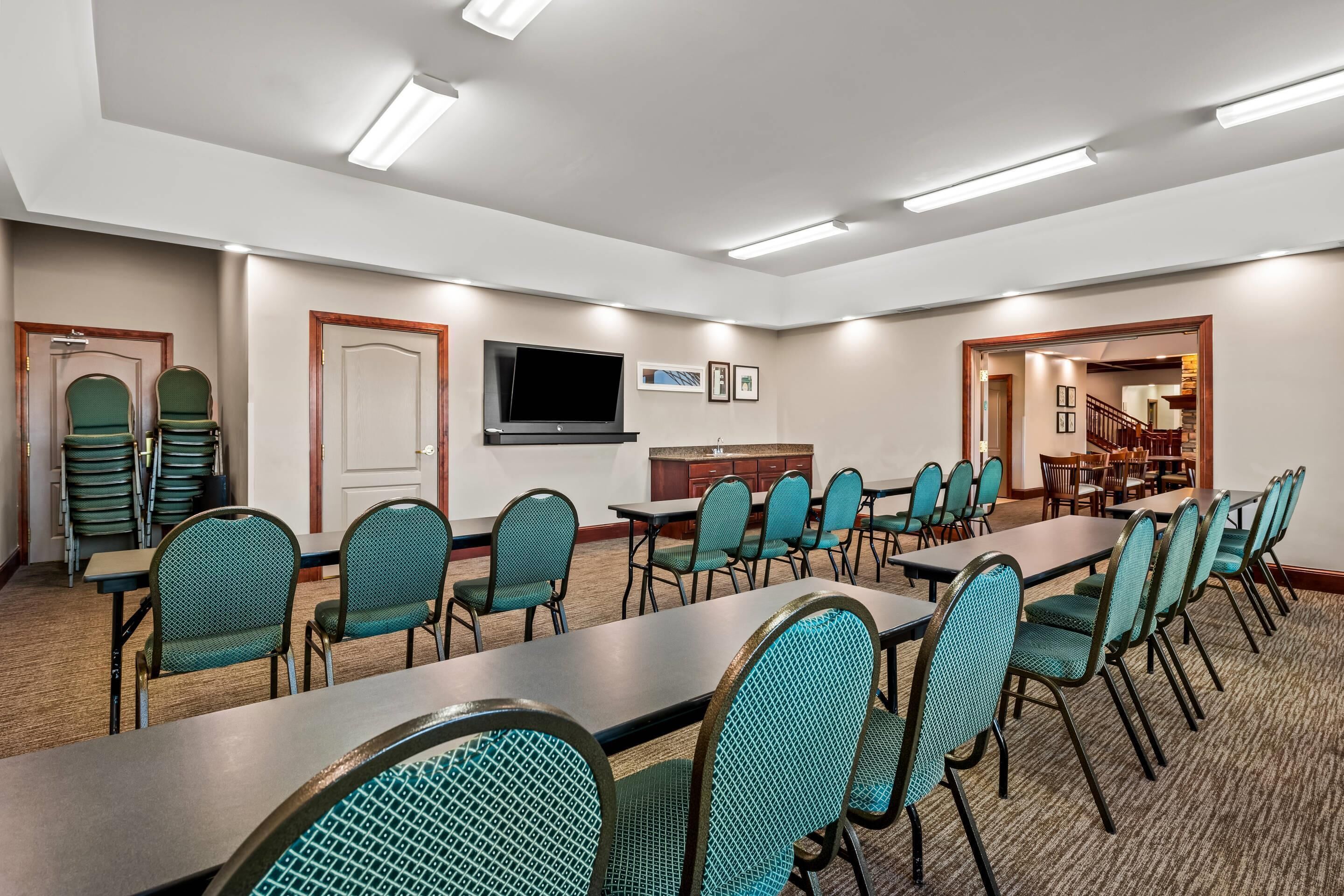 A conference room with a long table, chairs, a television, and framed pictures on the wall.