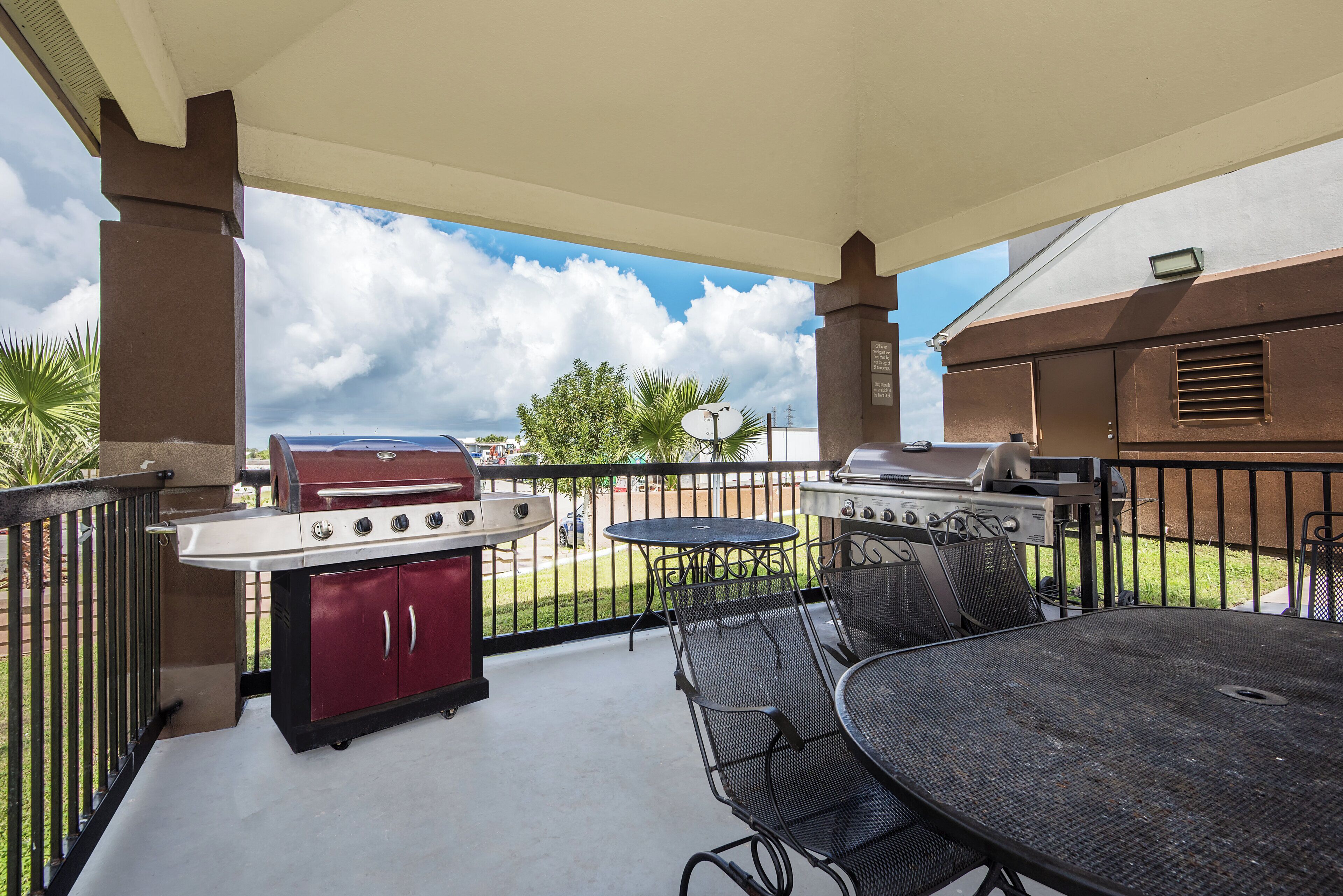 Une terrasse extérieure équipée de deux barbecues, d’une table ronde et de chaises.
