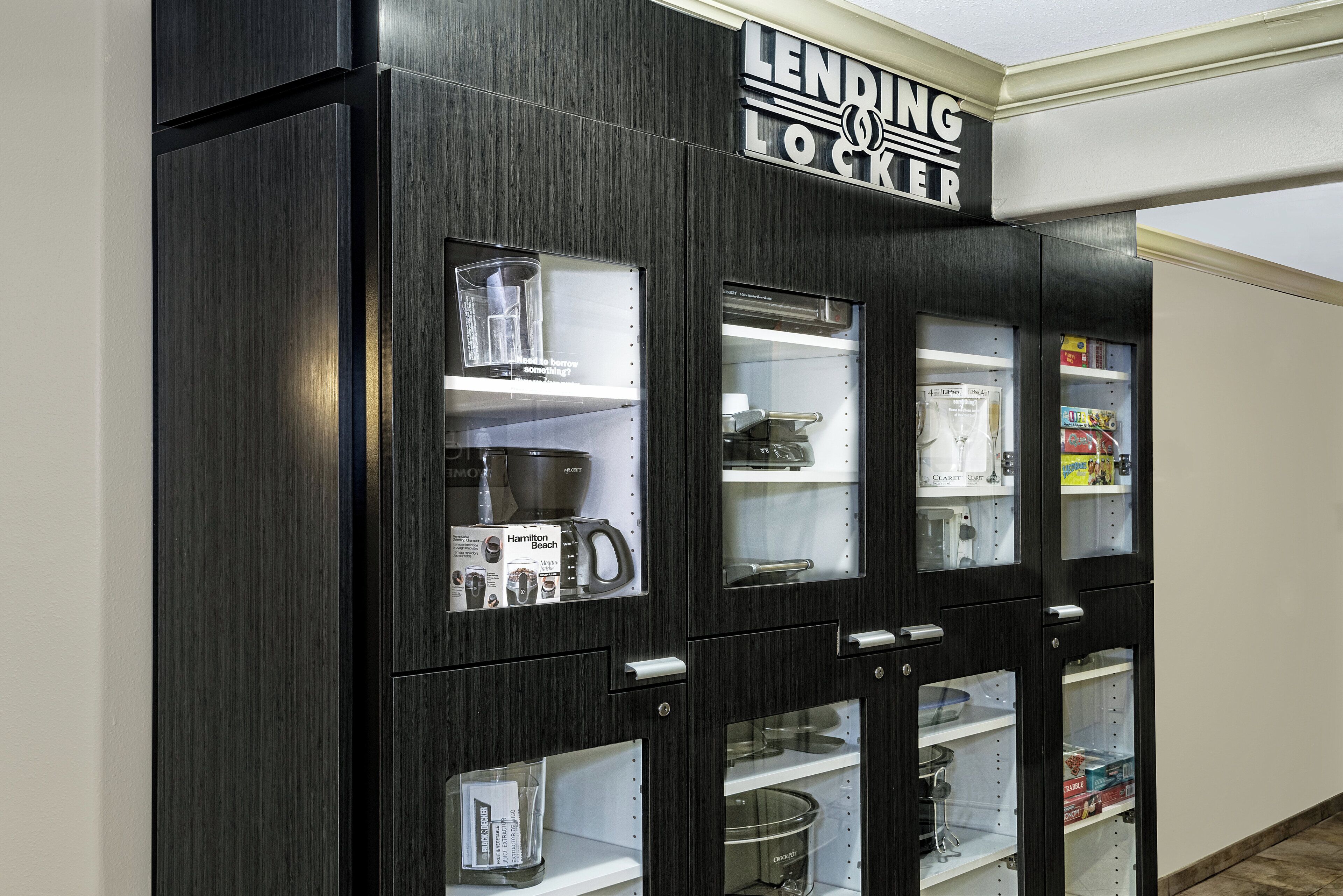A kitchen with a LENDING LOCKER and various appliances including a coffee maker and a crockpot.