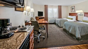 Een hotelkamer met kitchenette, twee bedden, een bureau en een televisie.