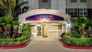 A hotel entrance with a sign reading 'CANDLEWOOD SUITES' and a gated driveway.