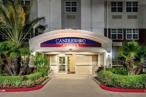 Entrada de un hotel con un letrero que dice 'CANDLEWOOD SUITES' y un camino de acceso con portones.