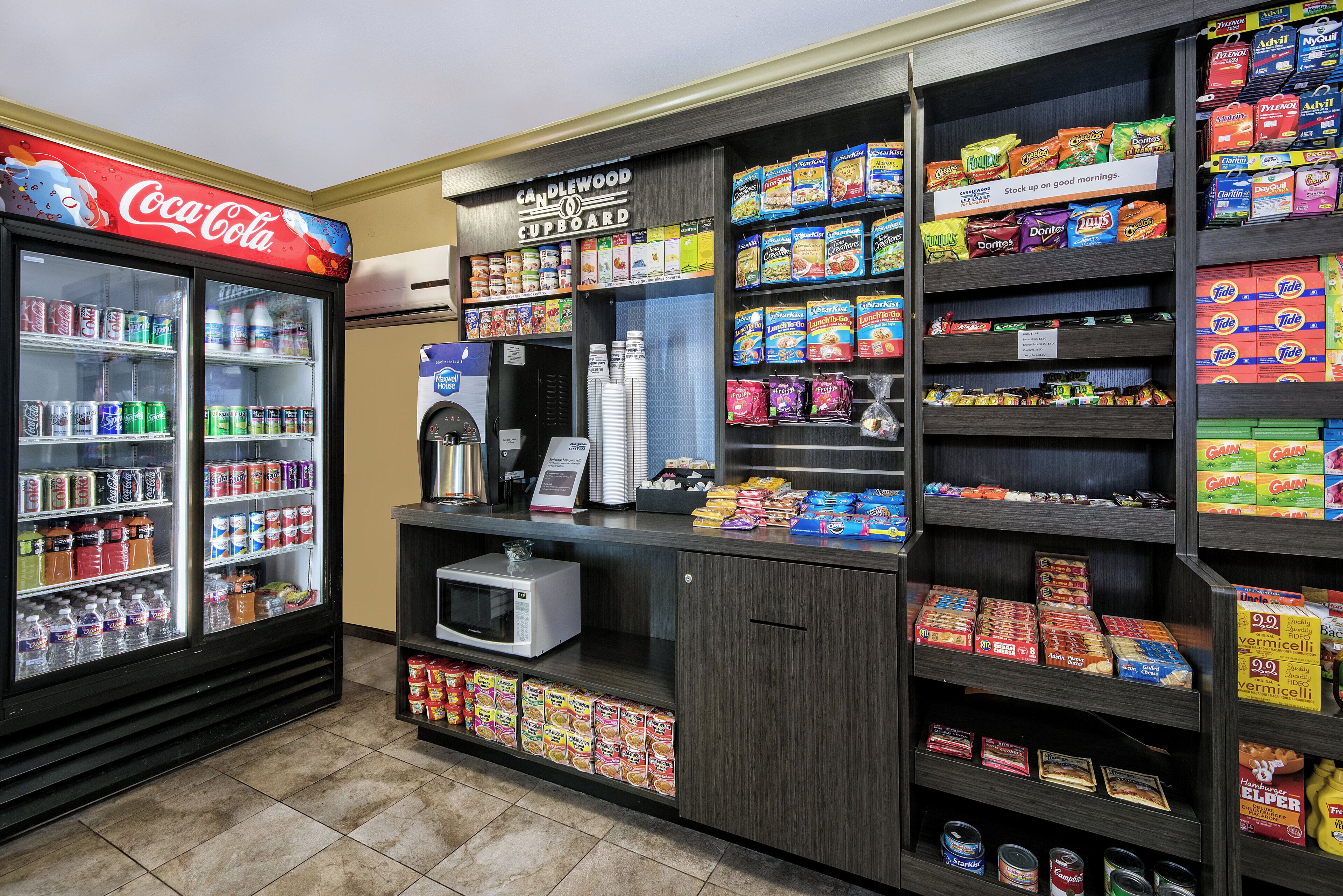 A vending machine area with various snack options, a microwave, and a Coca-Cola refrigerator.