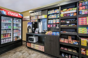 Un espace équipé d’un distributeur automatique proposant diverses collations, d’un four à micro-ondes et d’un réfrigérateur rempli de boissons Coca-Cola.