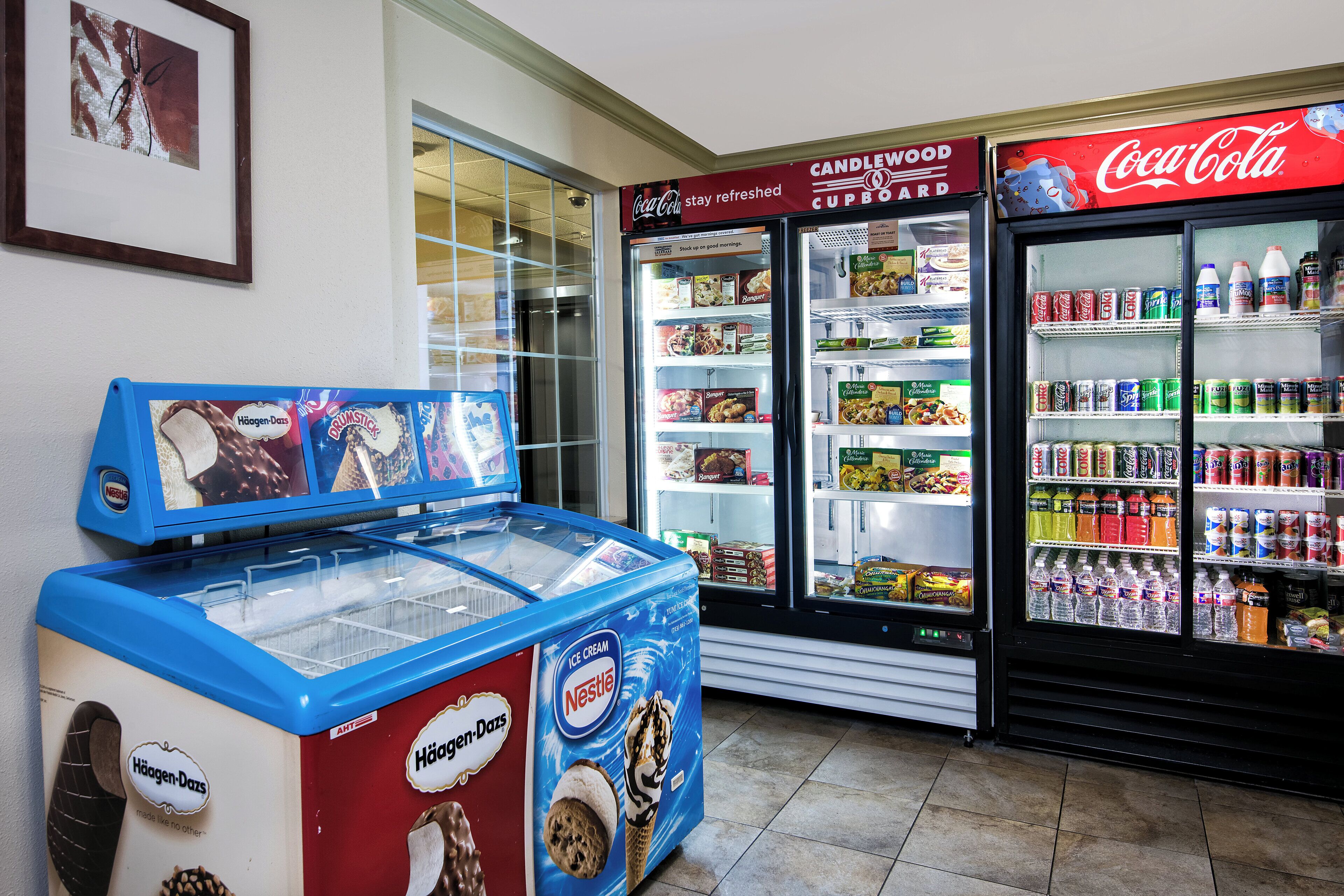 A vending machine with Häagen-Dazs ice cream and a Coca-Cola refrigerator stocked with various beverages.
