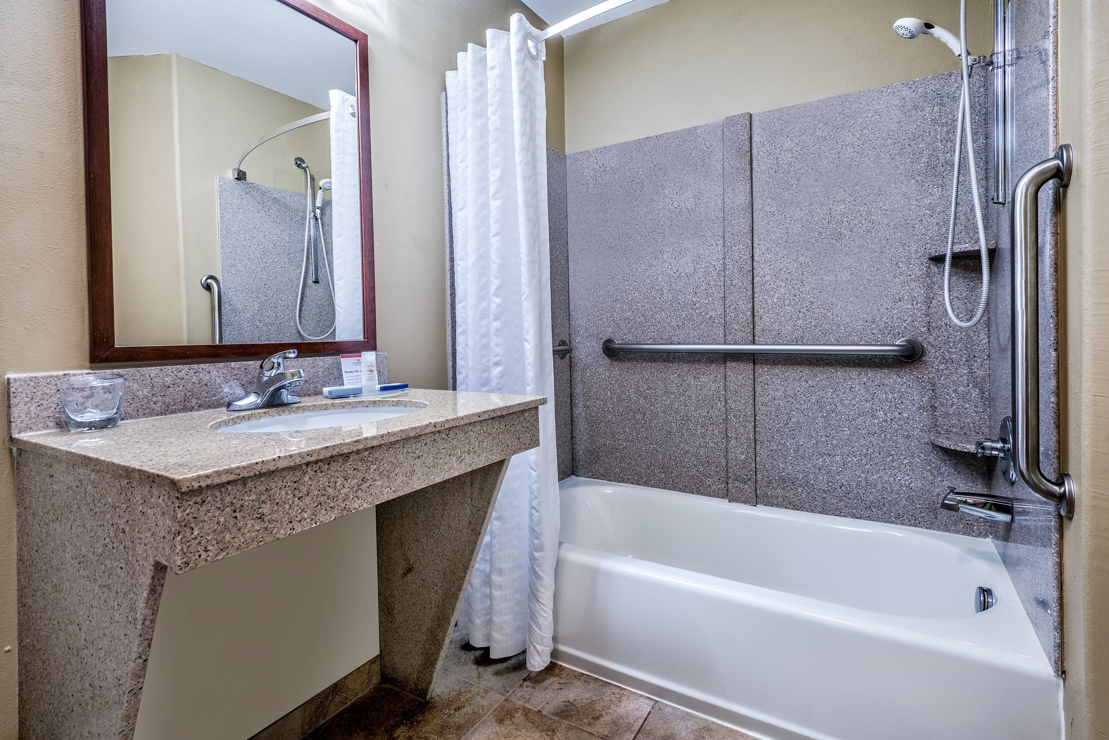 A bathroom with a bathtub, a shower, a sink, and a mirror.