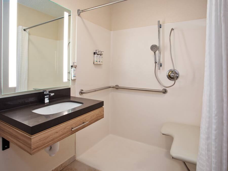 Une salle de bain moderne équipée d’un lavabo, d’un miroir, d’une douche et de toilettes.