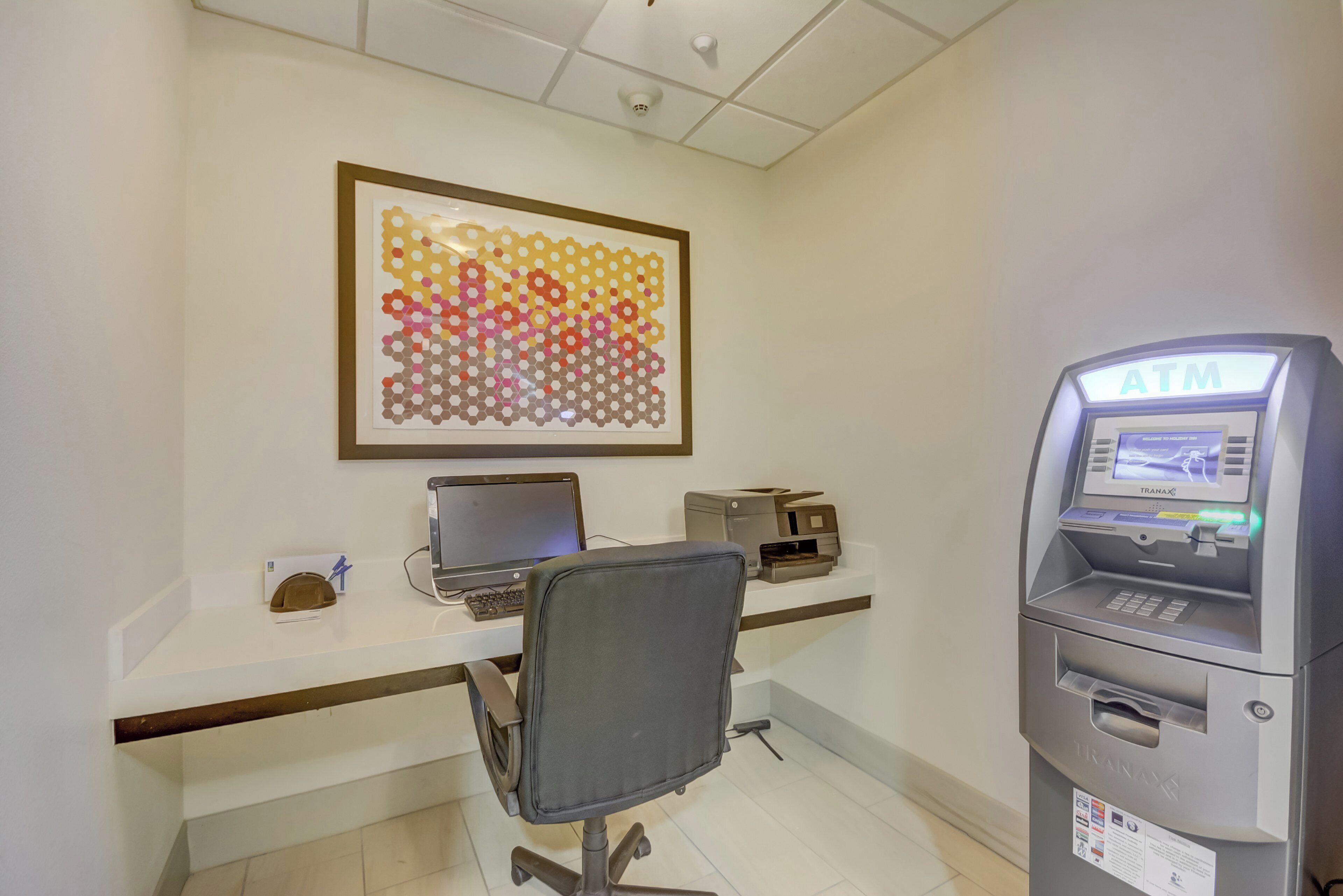 A reception desk with a computer, a printer, and an ATM.