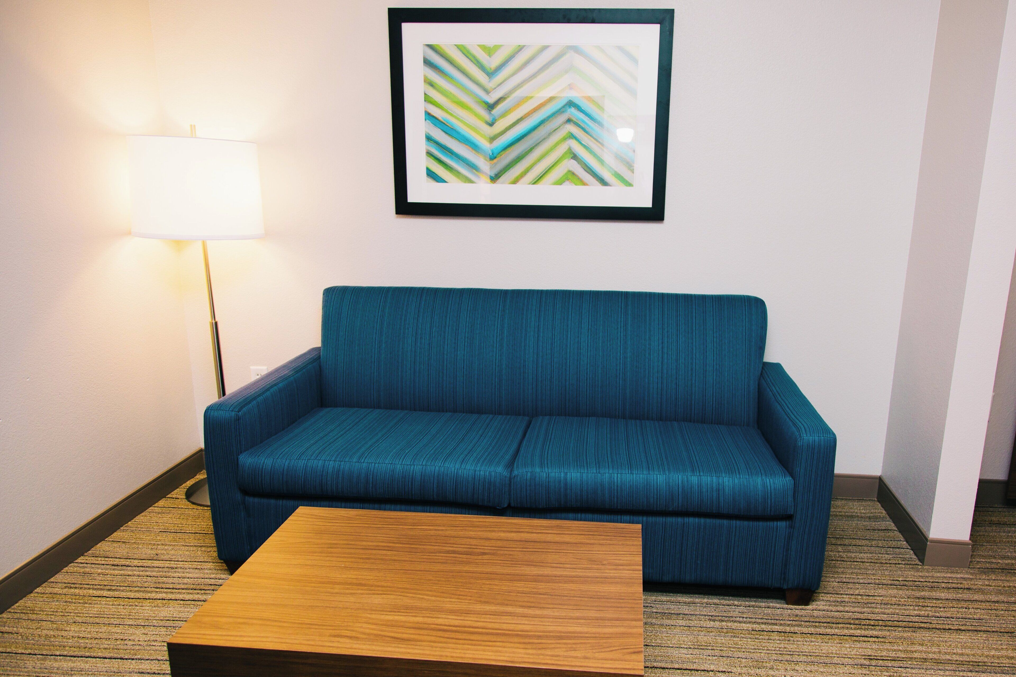 Una habitación con un sofá azul, una mesa de centro de madera y una lámpara de pie.