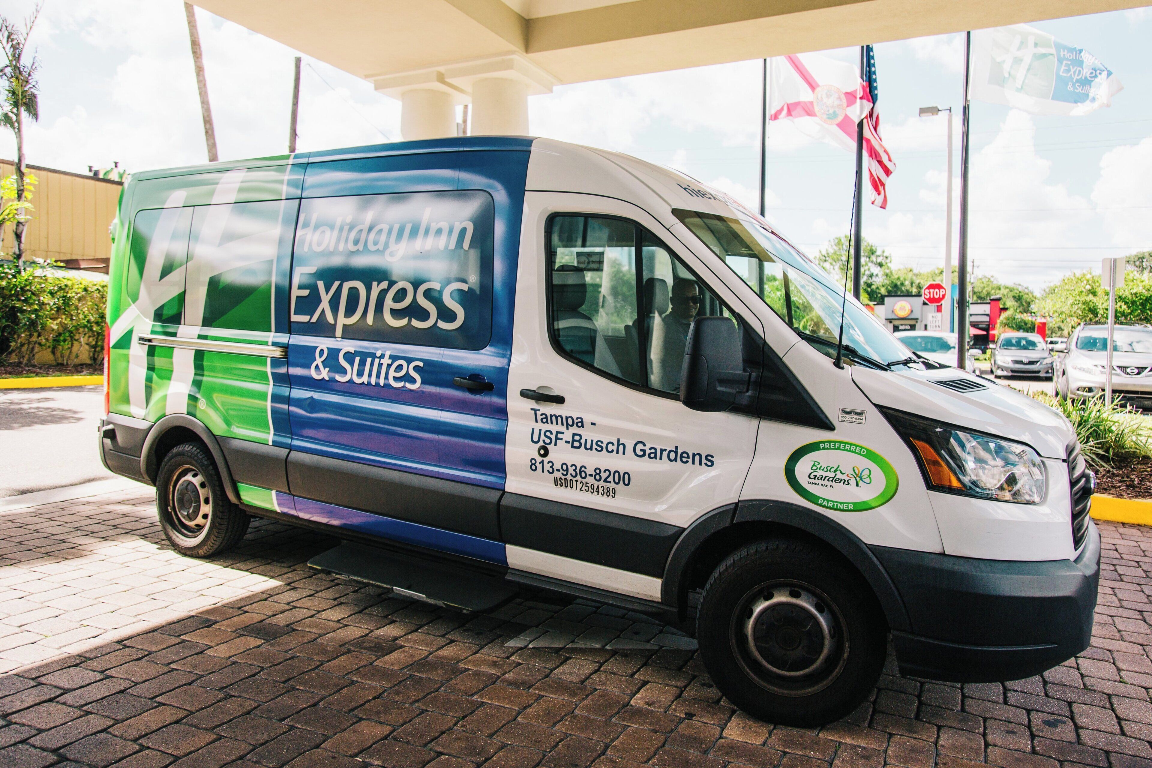 Un vehículo comercial con la marca 'Holiday Inn Express & Suites', estacionado en una gasolinera.