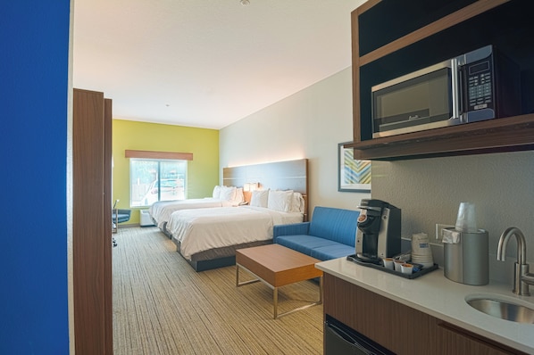 A hotel room with a bed, a sofa, a coffee machine, and a microwave.