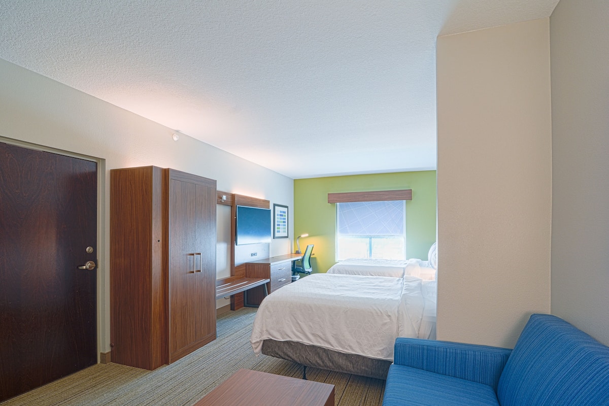 Ein Hotelzimmer mit Bett, Schreibtisch, Fernseher und Kleiderschrank.