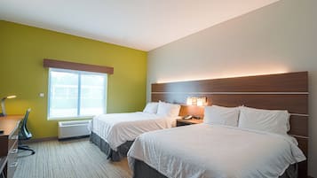 A hotel room with two beds, a desk, a chair, a window, and a wall-mounted phone.
