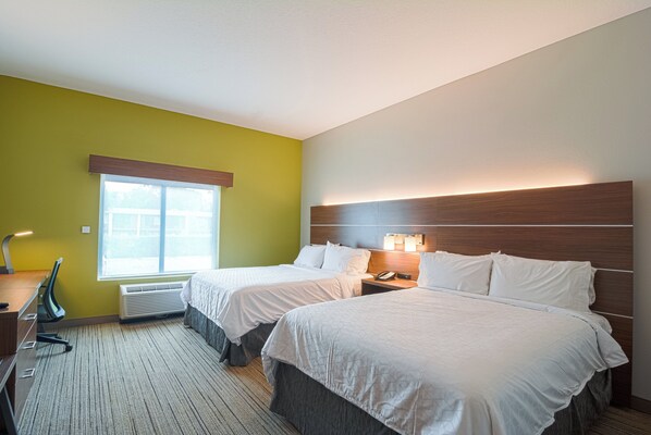 A hotel room with two beds, a desk, a chair, a window, and a wall-mounted phone.