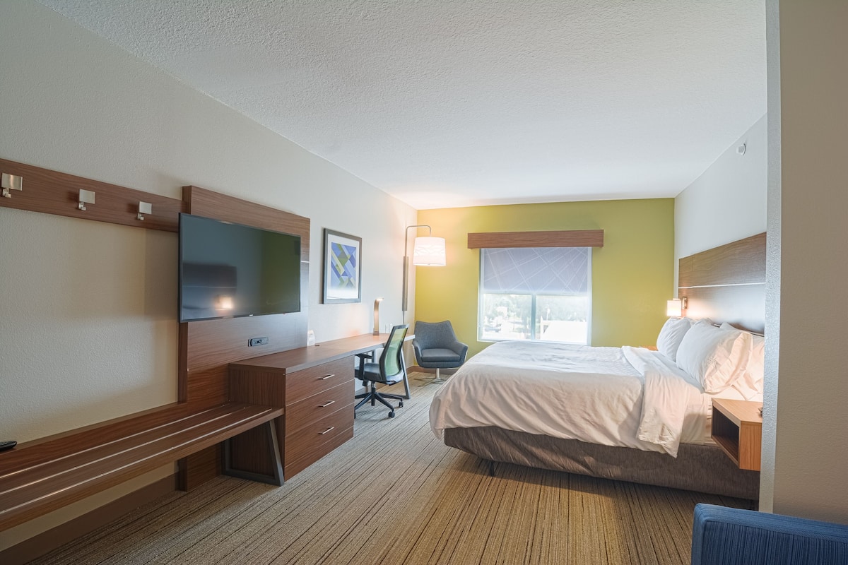 Ein Hotelzimmer mit Bett, Schreibtisch, Stuhl, Fernseher und Fenster.