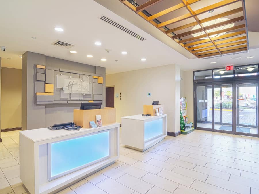 Een hotel receptie met een modern design, met een receptiebalie, een digitaal scherm en een plafond met houten latten.