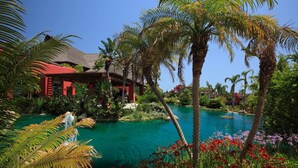 A resort with a clear pool, palm trees, and a red building. - Asia Gardens Hotel & Thai Spa, a Royal Hideaway Hotel (Benidorm)