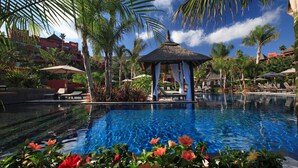 A swimming pool with lounge chairs and a gazebo, surrounded by palm trees and tropical plants. - Asia Gardens Hotel & Thai Spa, a Royal Hideaway Hotel (Benidorm)