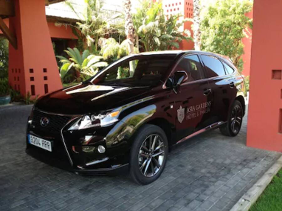 A black SUV parked in front of a building with a red facade and a logo that reads "Asian Gardens Hotel & Spa".