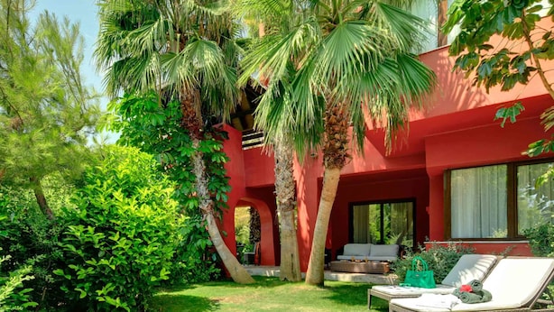 A red building with a covered outdoor seating area and lush greenery. - Asia Gardens Hotel & Thai Spa, a Royal Hideaway Hotel (Benidorm)