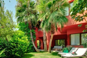 A red building with a covered outdoor seating area and lush greenery. - Asia Gardens Hotel & Thai Spa, a Royal Hideaway Hotel (Benidorm)