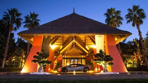 A building with a thatched roof and a car parked in front. - Asia Gardens Hotel & Thai Spa, a Royal Hideaway Hotel (Benidorm)