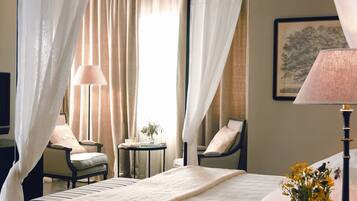 A hotel room with a bed, two chairs, a small table with a lamp, and a vase with flowers.