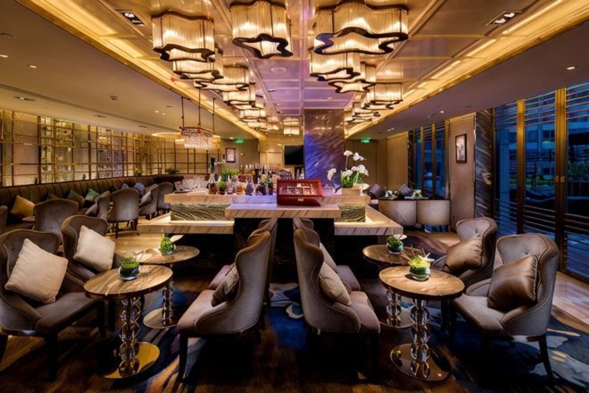 A modern hotel lobby with a bar area, seating arrangements, and a view of the city.
