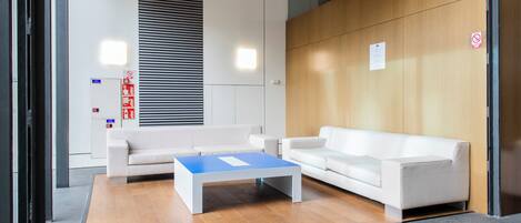 Un vestíbulo moderno con dos sofás blancos, una mesa de centro azul y una pared de acento de madera.