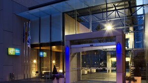 Entrada d'un hotel modern amb portes de vidre, una escala visible i un senyal que indica que és un Holiday Inn Express.