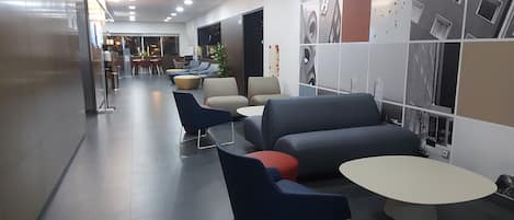 A modern lounge area with seating arrangements and a wall decorated with architectural images.