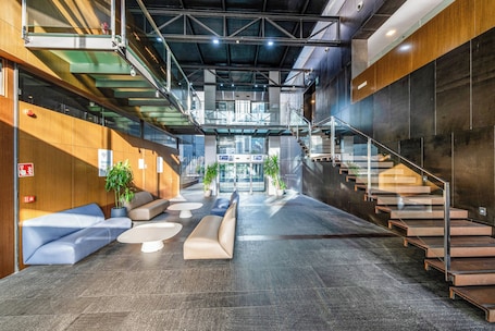A modern lobby with a staircase, seating areas, and potted plants.. Holiday Inn Express Barcelona City 22@ by IHG