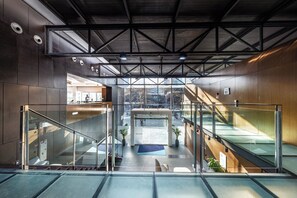 A modern interior with glass railings, a central staircase, and a view through large windows. - Holiday Inn Express Barcelona City 22@ by IHG (Barcelona)
