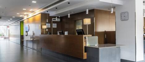 A modern reception area with a wooden reception desk, a clock on the wall, and a clean, well-lit interior.
