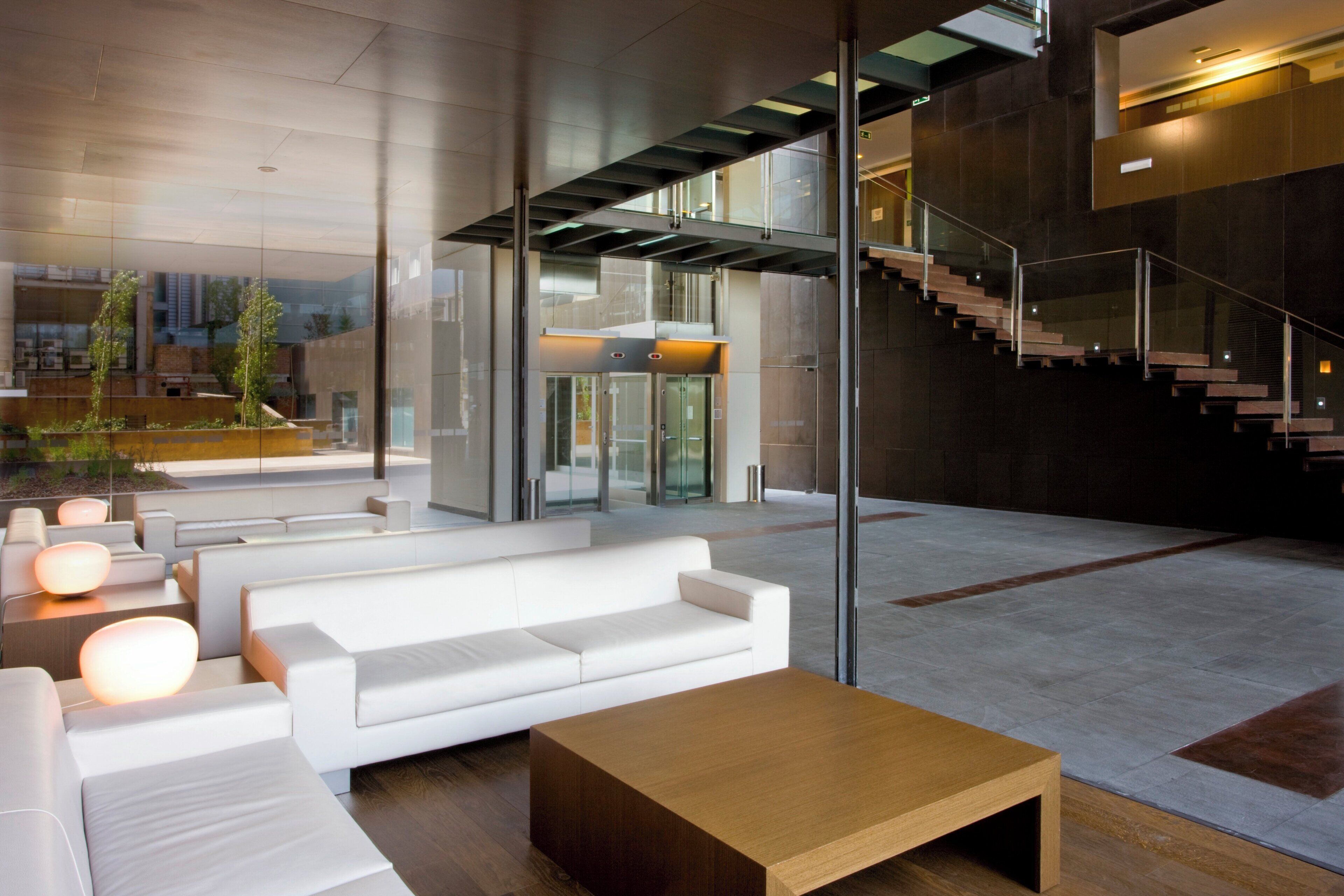 Eine moderne Lobby mit einem weißen Sofa, einem Holztisch und einer Treppe.