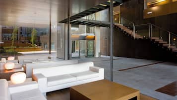 Eine moderne Lobby mit einem weißen Sofa, einem Holztisch und einer Treppe.