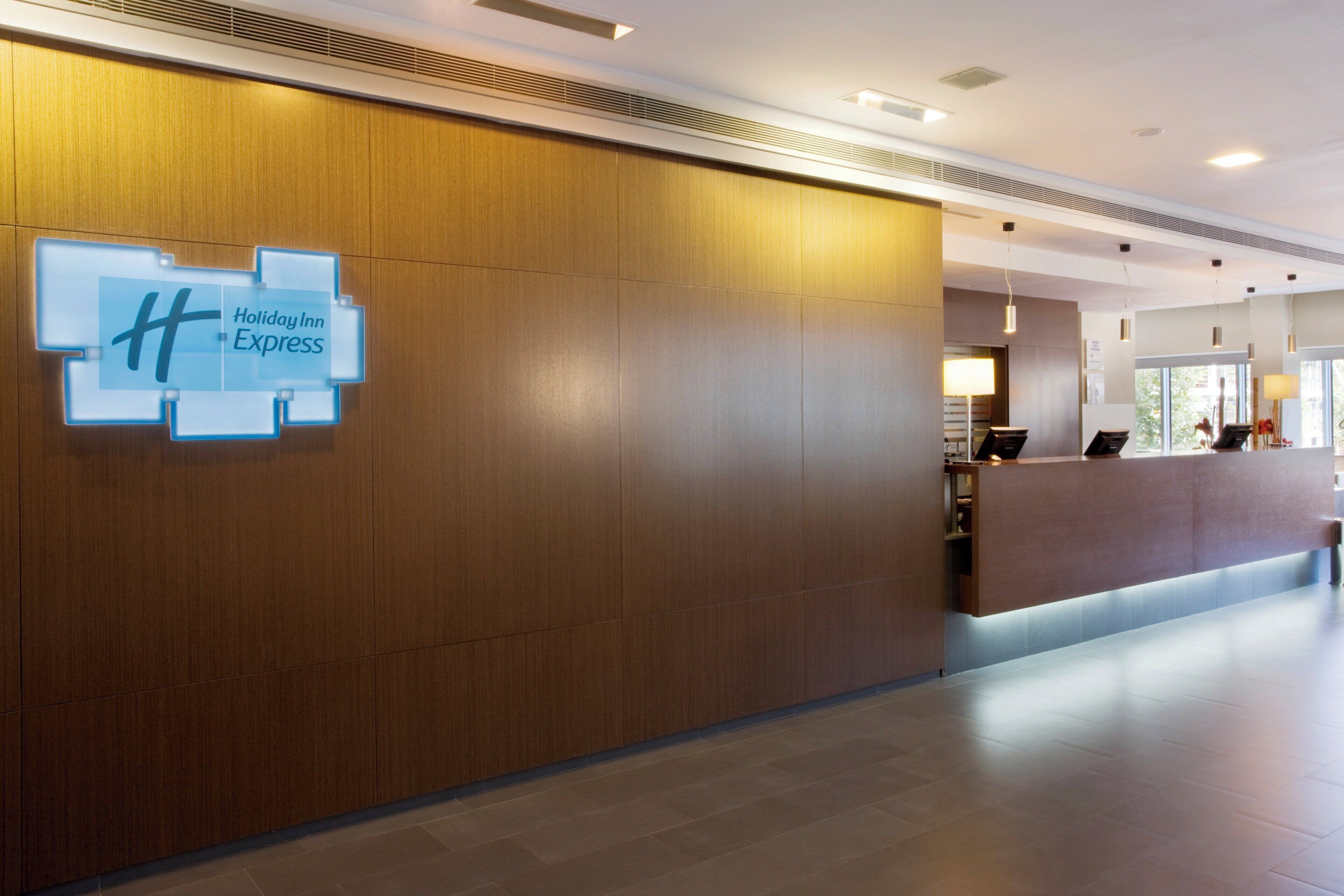 L’espace d’accueil d’un hôtel Holiday Inn Express, avec un mur revêtu de panneaux en bois et un comptoir de réception.