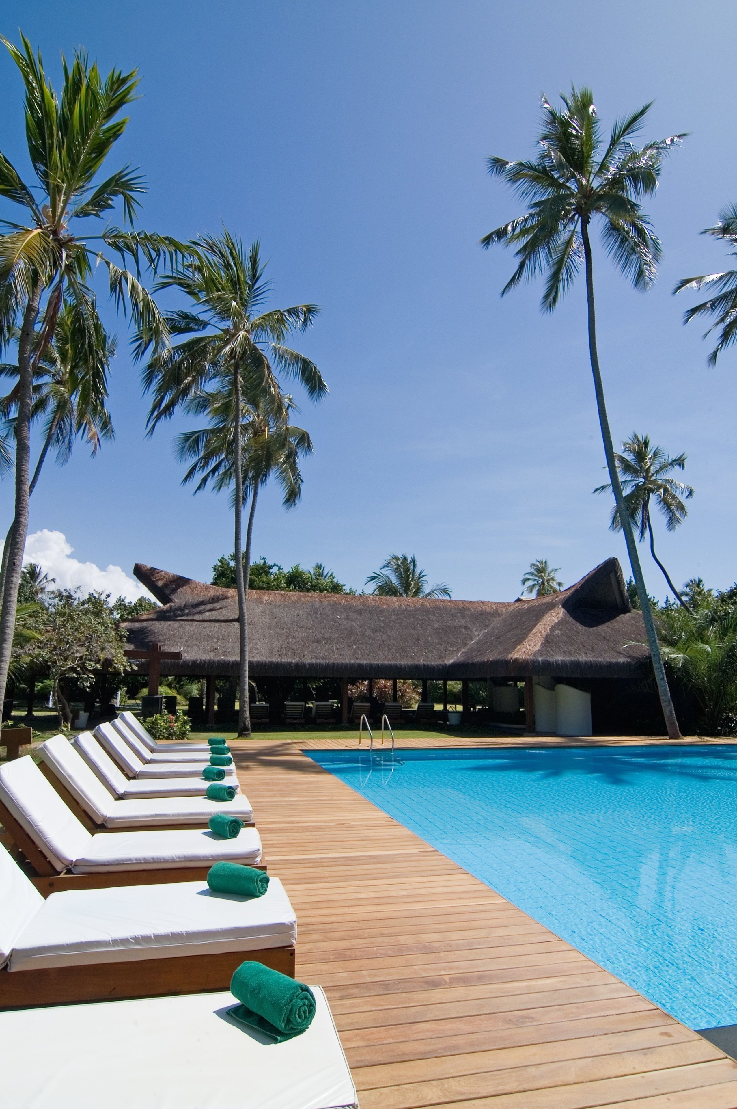 A poolside area with lounge chairs and a thatched-roof building.