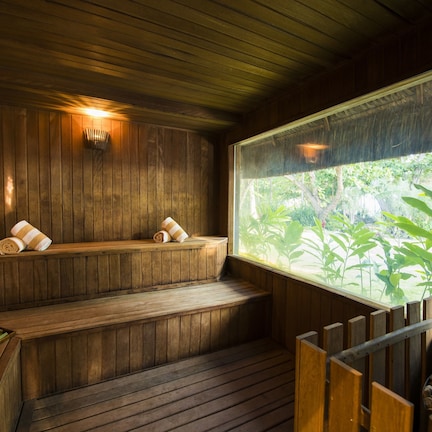 A wooden sauna with benches and a window offering a view of greenery.