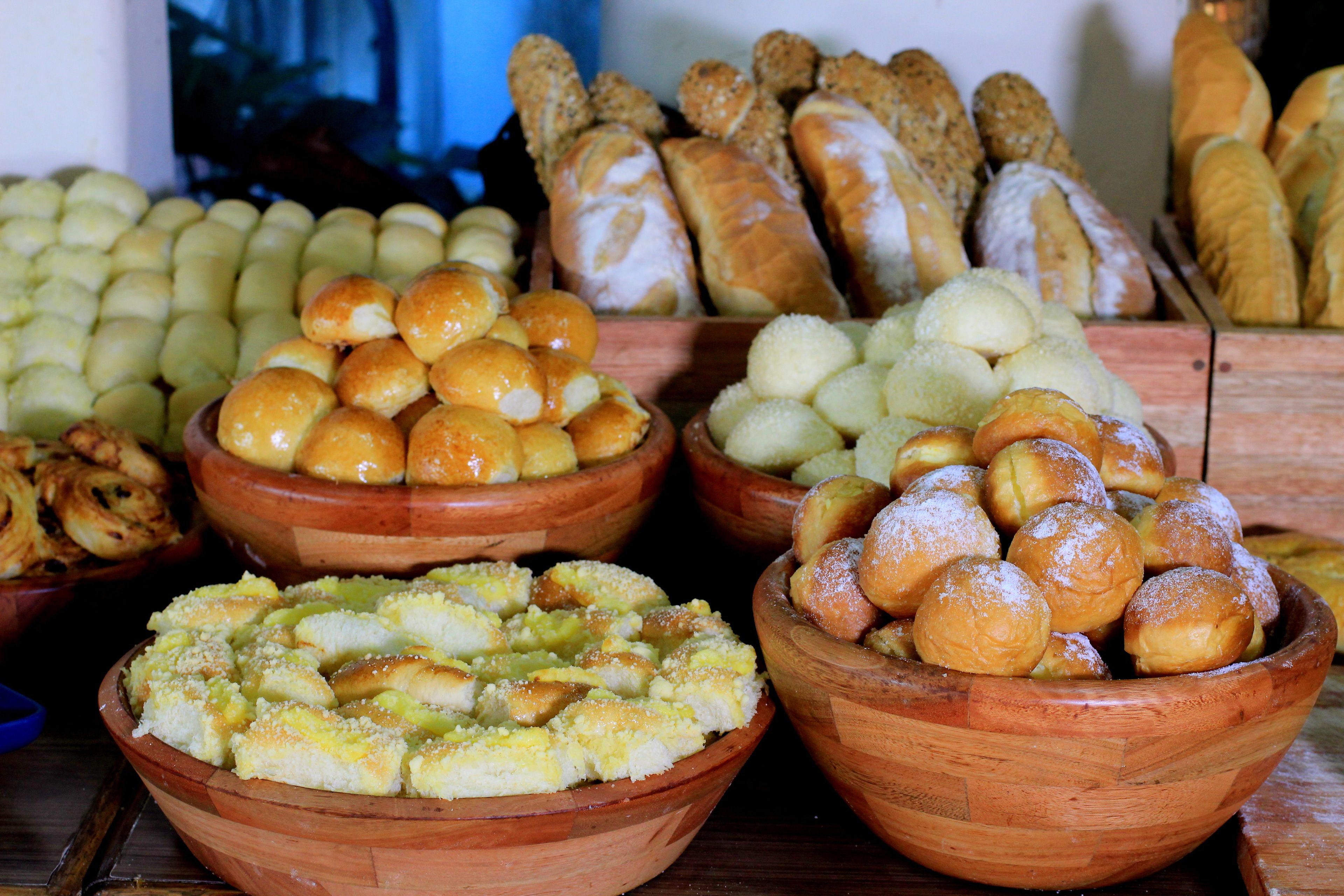 Diversos produtos de panificação expostos em taças de madeira.