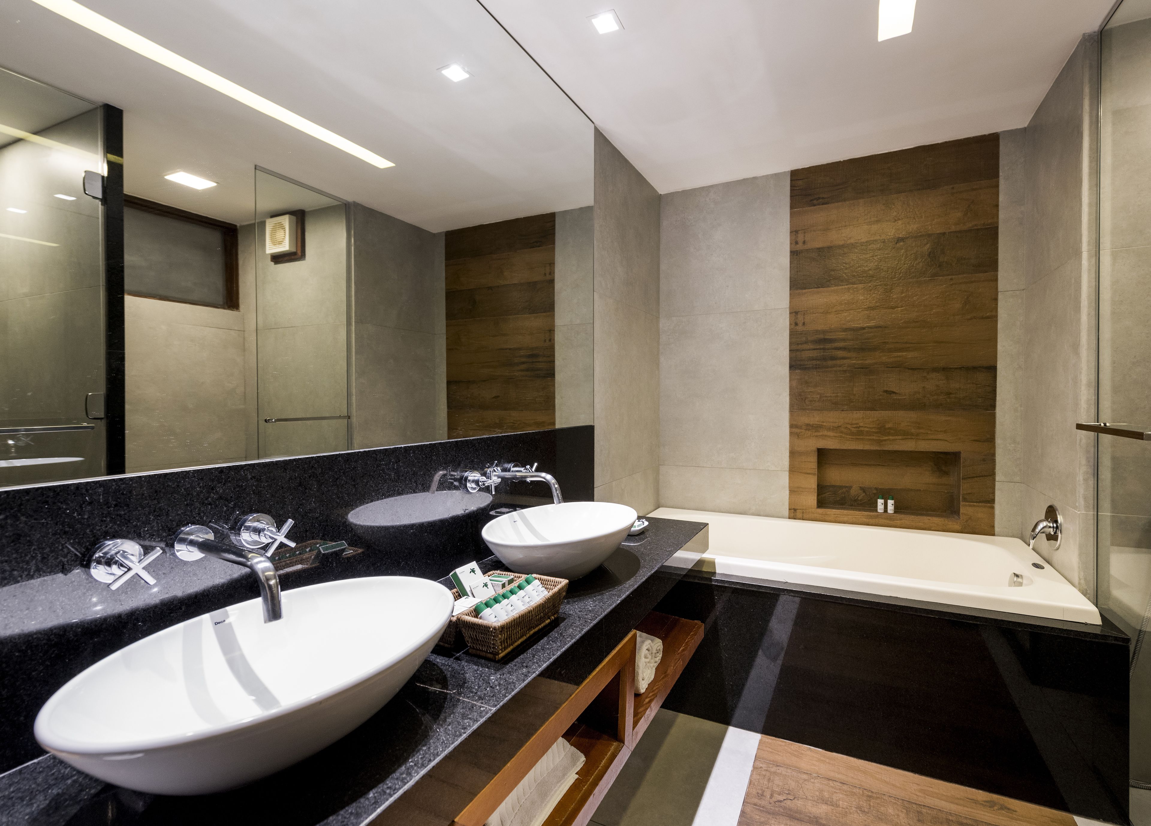 A modern bathroom with two sinks, a bathtub, and a large mirror.