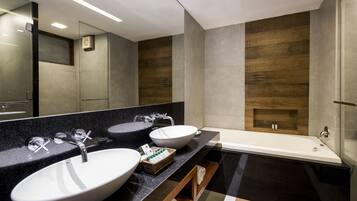 A modern bathroom with two sinks, a bathtub, and a large mirror.