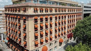 Un hotel de varios pisos con balcones, techo plano y una bandera.