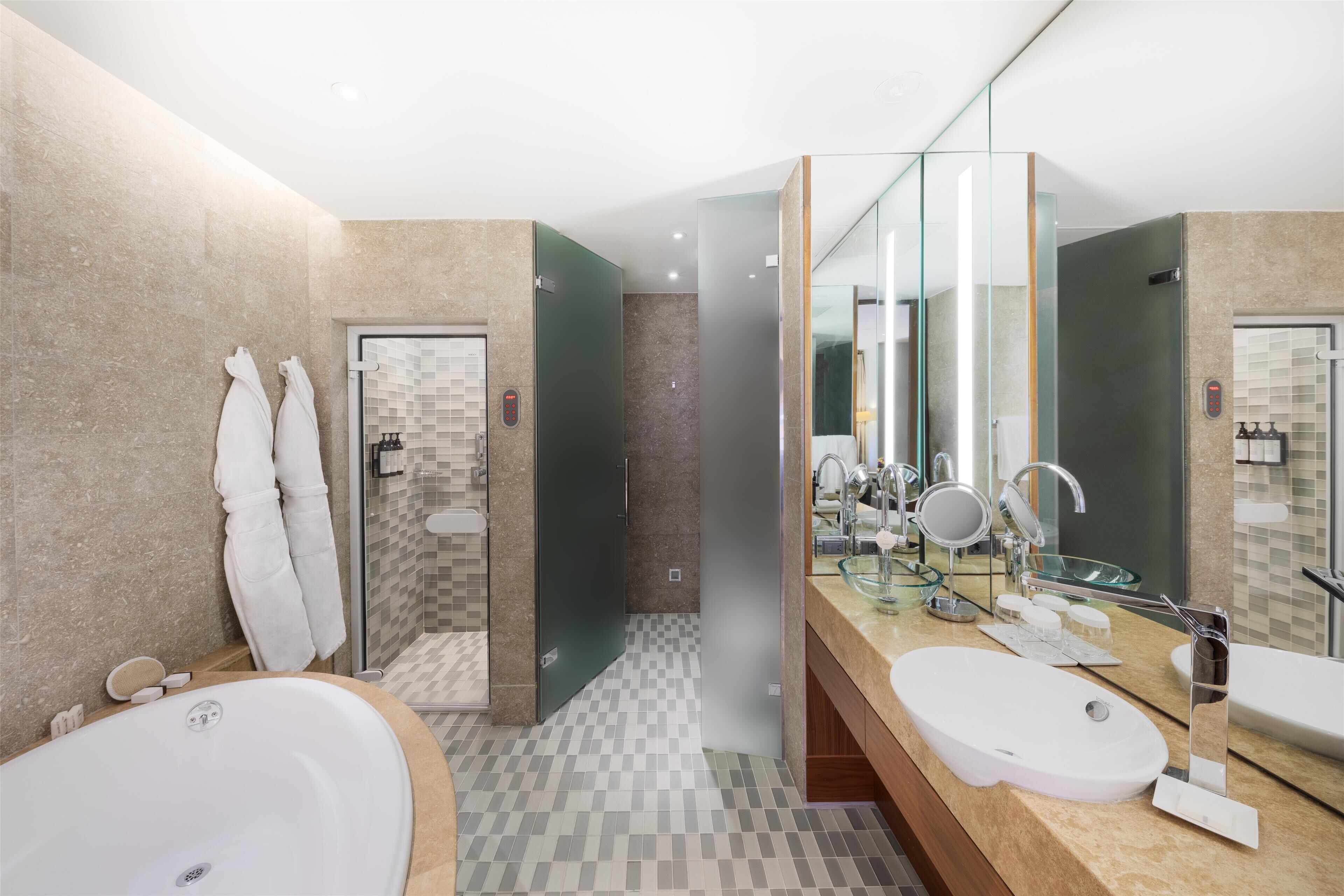 A modern bathroom with a large bathtub, a double sink vanity, and a large mirror.