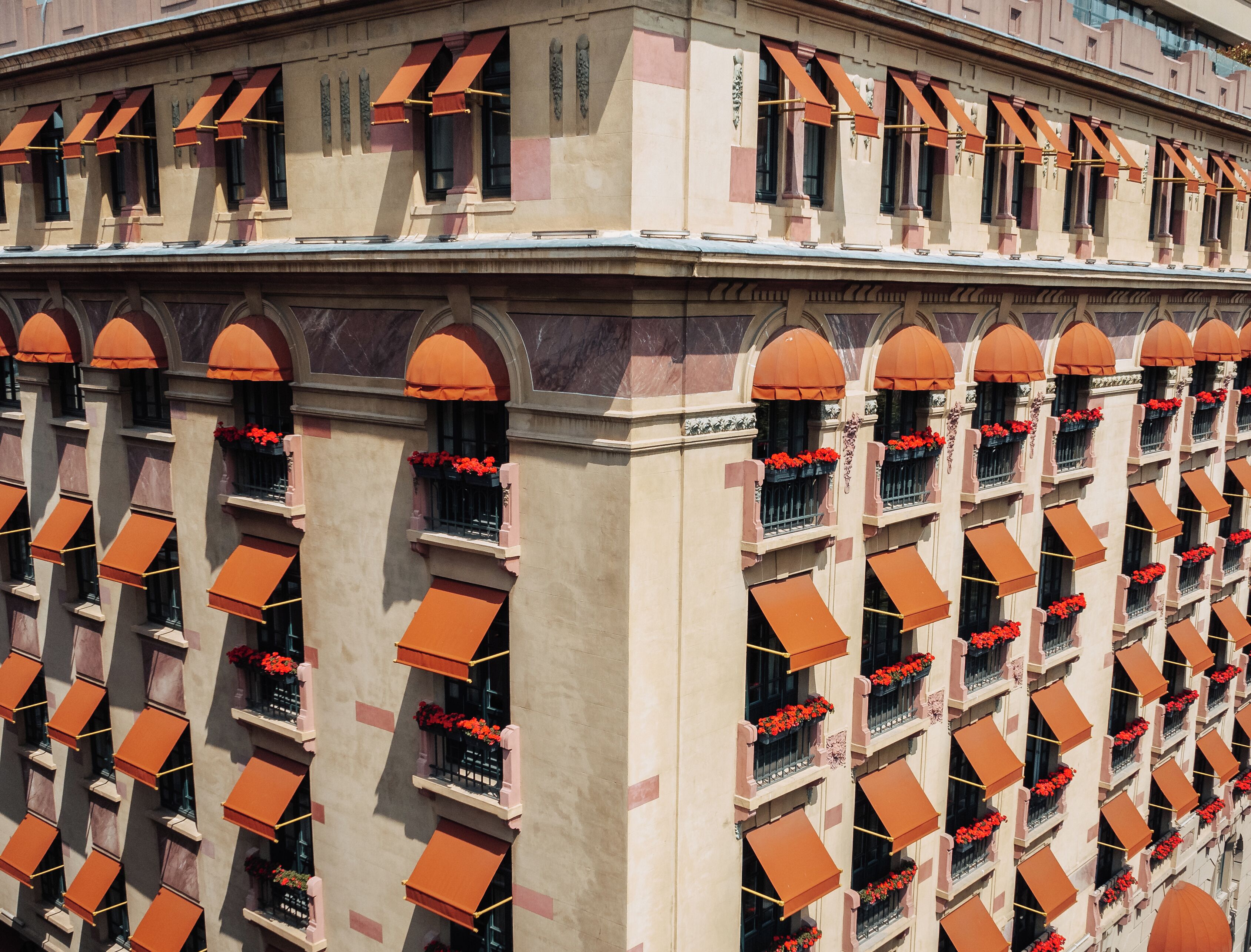 Un edificio con varios balcones, cada uno con toldos naranjas y flores rojas.