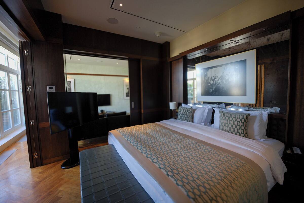 Una habitación de hotel moderna con una cama grande, un televisor de pantalla plana y un ventanal amplio.