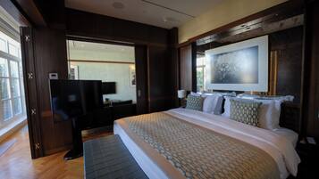 A modern hotel room with a large bed, a flat-screen TV, and a large window.